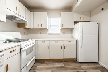 A white kitchen with a refrigerator, oven, and cabinets.
